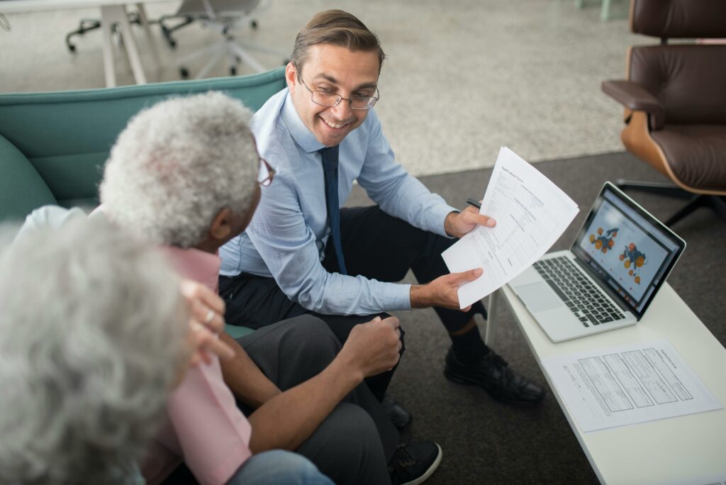 Financial advisor smiling and explaining paperwork to senior clients, representing retirement planning and addressing common misconceptions