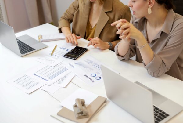 Two professionals reviewing financial reports and investment charts with laptops and a calculator, illustrating risk-managed investment planning