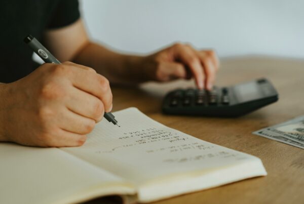 Close-up of a person writing in a financial notebook and using a calculator, symbolizing goal-oriented portfolio planning and personal finance strategy