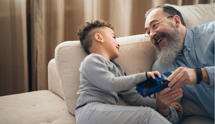 Joyful grandfather playing with his grandson on a couch, symbolizing a secure and fulfilling retirement