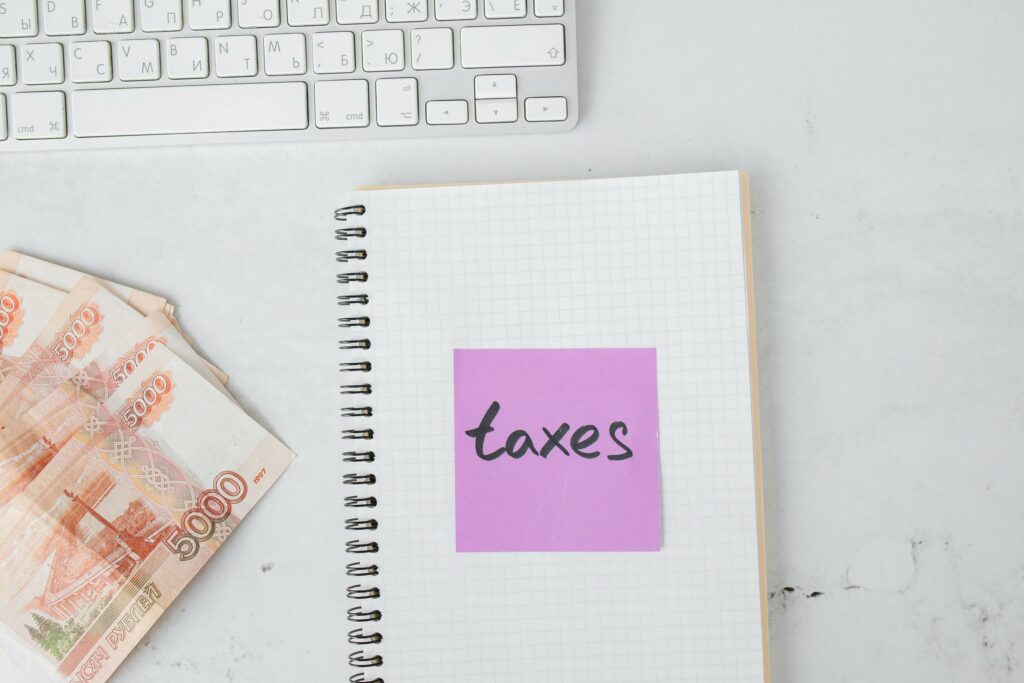 Notebook labeled “taxes” with currency notes and a keyboard, representing business tax planning and financial organization in 2025