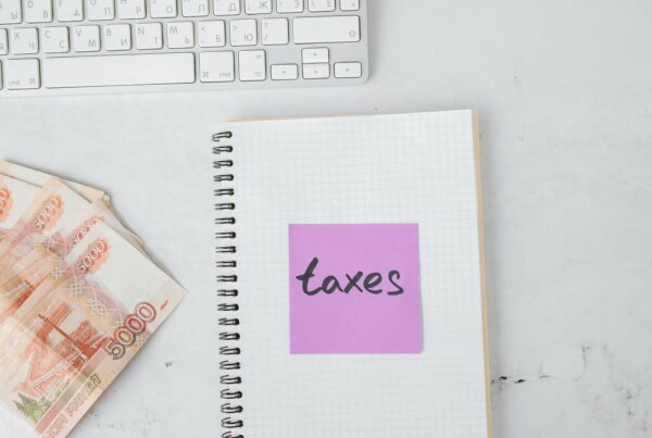 Notebook labeled “taxes” with currency notes and a keyboard, representing business tax planning and financial organization in 2025