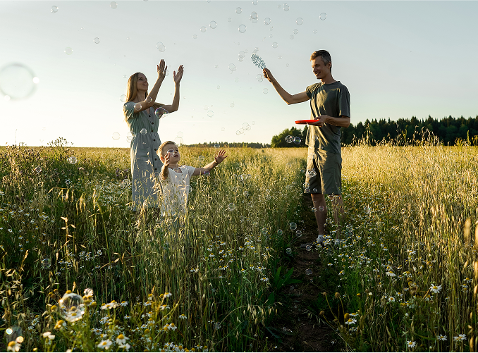 Happy family playing with bubbles in a sunny meadow, symbolizing clarity, joy, and a future built with thoughtful financial strategy